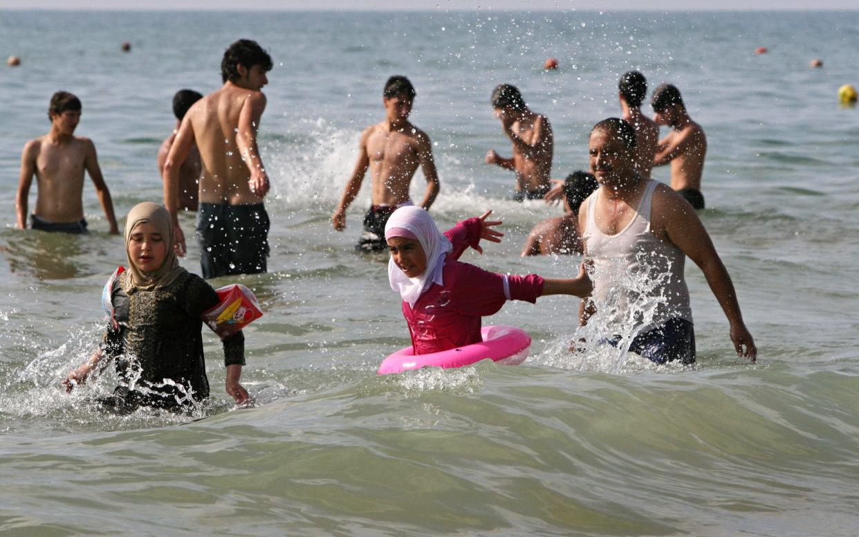 Lebanese play in the Mediterranean Sea in the southern seaport of Sidon - AP