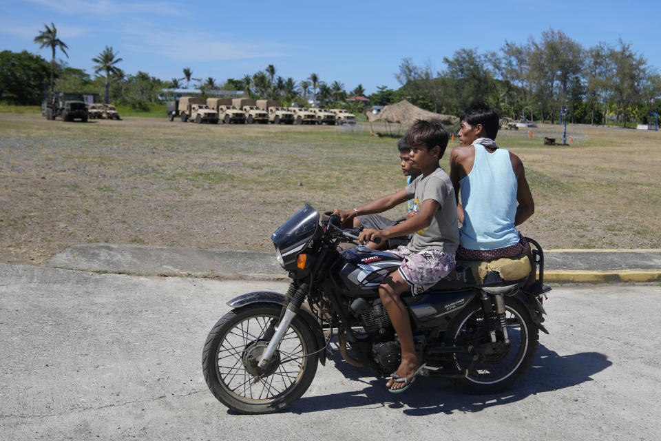 Residents ride a tricycle past U.S. military vehicles at the Naval Base Camilo Osias, Santa Ana, Cagayan province, northern Philippines on Monday, May 6, 2024. American and Filipino troopers are currently in the area to conduct annual combat-readiness exercises called Balikatan, Tagalog for shoulder-to-shoulder. (AP Photo/Aaron Favila)