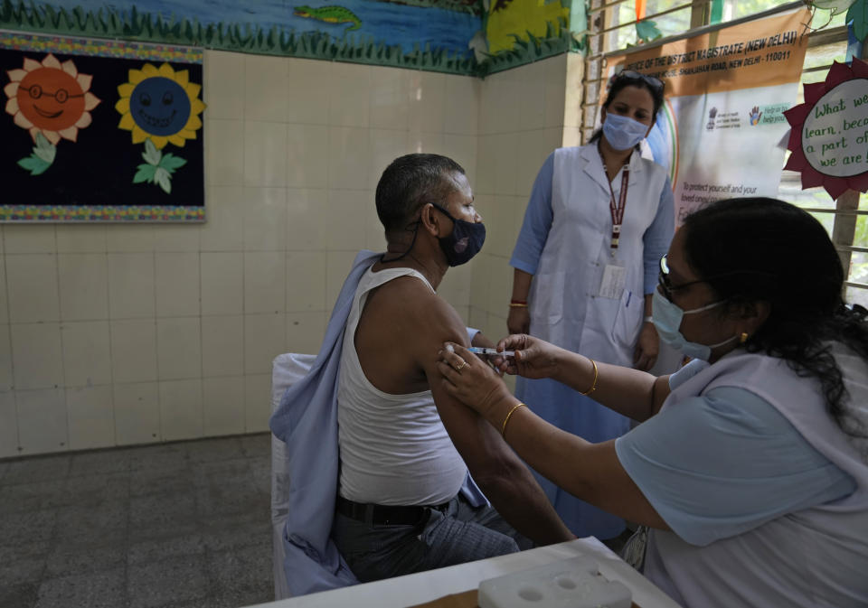 A health worker administers the vaccine for COVID-19 at a vaccination center set up at a government-run school in New Delhi, India, Tuesday, Sept. 21, 2021. India, the world's largest vaccine producer, will resume exports and donations of surplus coronavirus vaccines in October after halting them during a devastating surge in domestic infections in April, the health minister said Monday. (AP Photo/Manish Swarup)