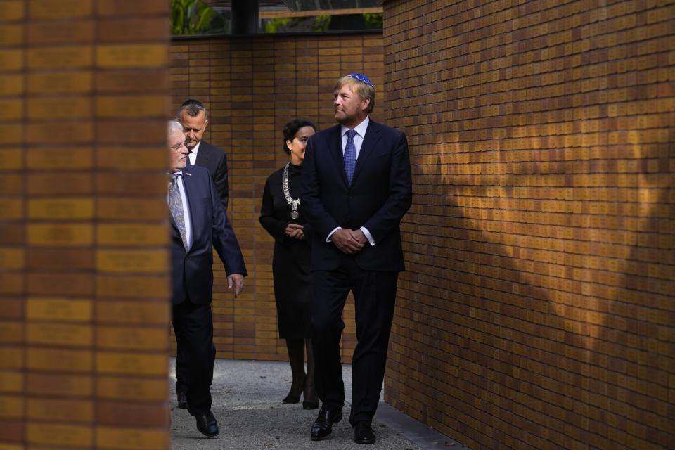 King Willem-Alexander, right, walks along walls with name stones after officially unveiling a new monument in the heart of Amsterdam's historic Jewish Quarter on Sunday, Sept. 19, 2021, honoring the 102,000 Dutch victims of the Holocaust. Designed by Polish-Jewish architect Daniel Libeskind, the memorial is made up of walls shaped to form four Hebrew letters spelling out a word that translates as "In Memory Of." The walls are built using bricks each of which is inscribed with the name of one of the 102,000 Jews, Roma and Sinti who were murdered in Nazi concentration camps during World War II or who died on their way to the camps. (AP Photo/Peter Dejong)