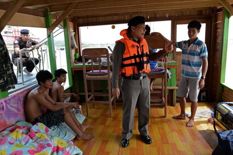 Thai Marine Border Police speak to the Laotian crew of a boat during a search of the vessel on the Mekong river, May 28, 2013. A dedicated Thai unit of 30 policemen, with three boats, now patrols a 17-kilometre (11 mile) stretch of the river border