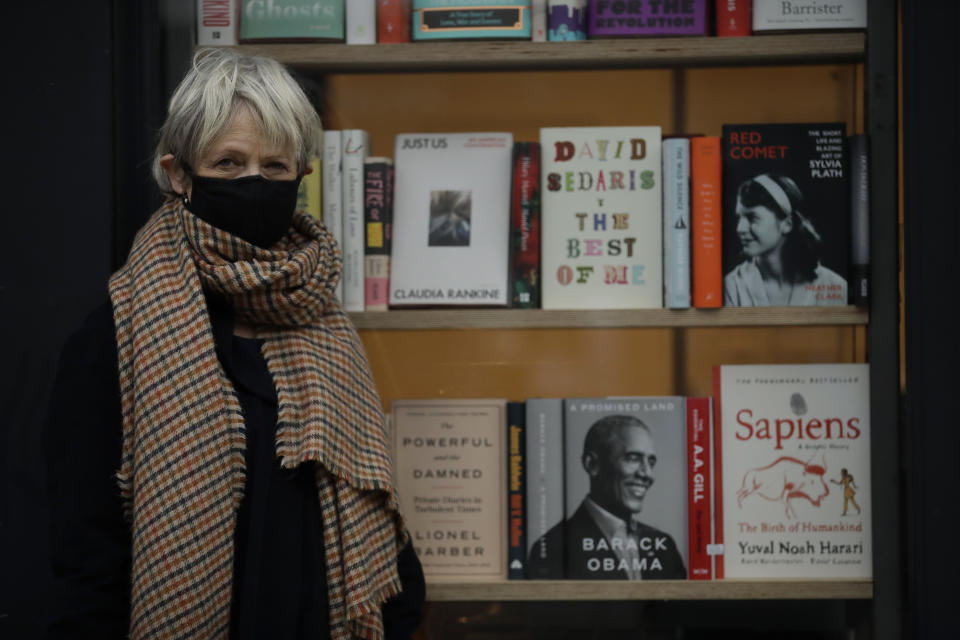 Jane Howe, the owner of the Broadway Bookshop poses for a portrait outside her shop which is temporarily closed for in-store browsing but open for customers to purchase books online and collect them from outside the shop door, during England's second coronavirus lockdown, on Broadway Market in Hackney, east London, Tuesday, Nov. 17, 2020. Small businesses around the world are fighting for survival amid the economic fallout from the coronavirus pandemic. Whether they make it will affect not just local economies but the fabric of communities.(AP Photo/Matt Dunham)