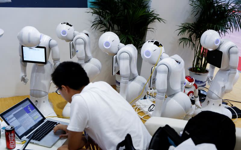 FILE PHOTO: A man programs SoftBank Robotics "Pepper" robots at the 2017 World Robot Conference in Beijing