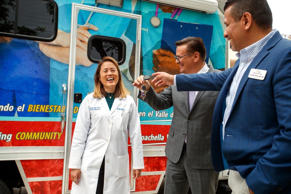 Desert Physicians Medical Group Health Chief Academic Officer, Dr. Gemma Kim, laughs as Desert Healthcare District and Foundation CEO Conrado Barzaga, center, and Desert Healthcare District and Foundation Chief of Community Engagement Alejandro Espinoza hand over the keys to the new mobile medical clinic at Desert Regional Medical Center in Palm Springs, Calif., on Friday, Dec. 2, 2022. DPMG will be operating the mobile medical clinic. 