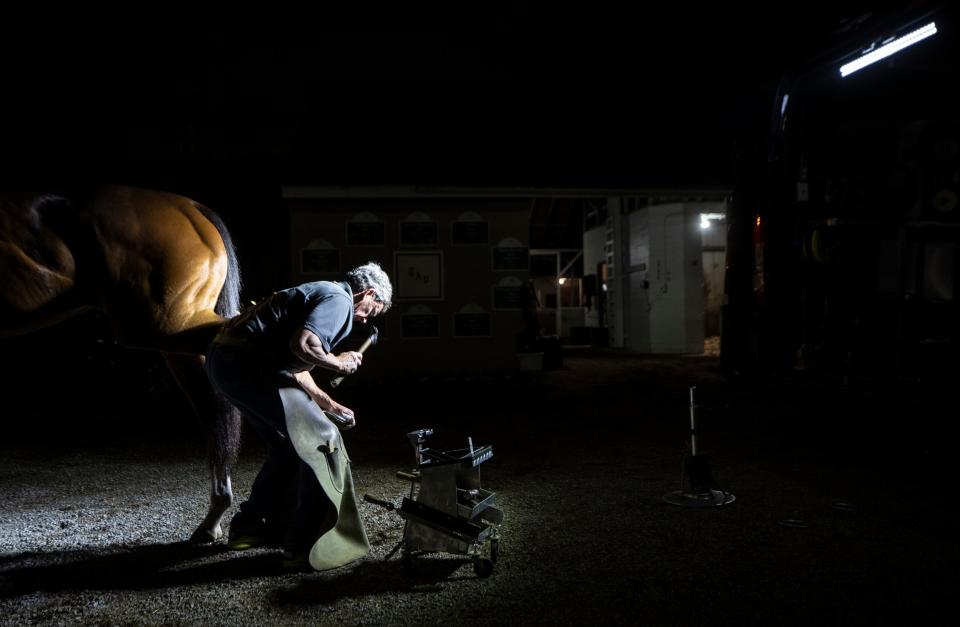 Farrier Jimmy Costello puts new shoes on a horse in the pre dawn hours on the backside of Churchill Downs. May 1, 2022