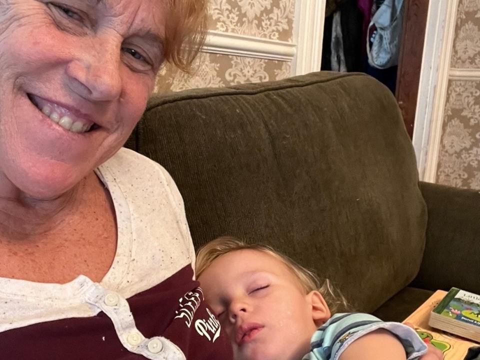 Older mom Barb Higgins cuddles her toddler son on a couch.