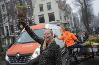 On the day stores in Amsterdam and across the Netherlands cautiously re-opened after weeks of coronavirus lockdown, the Dutch capital's mood was further lightened by dashes of color in the form of thousands of free bunches of tulips handed out by growers in Amsterdam, Netherlands, Saturday, Jan. 15, 2022. (AP Photo/Peter Dejong)