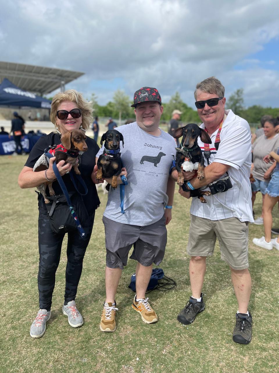 From left, Maria Pronske holds Otto, Thomas Pronske holds Johnny, and Erik Pronske holds Rhett ahead of the 2023 Buda Wiener Dog Races.