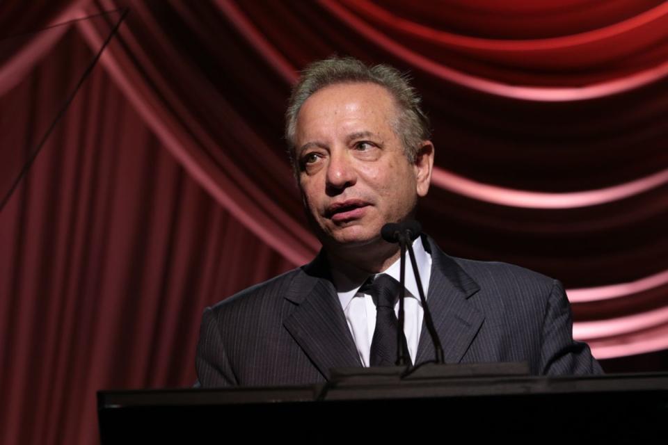 Carmen A. Puliafito is shown at a podium speaking into a microphone.