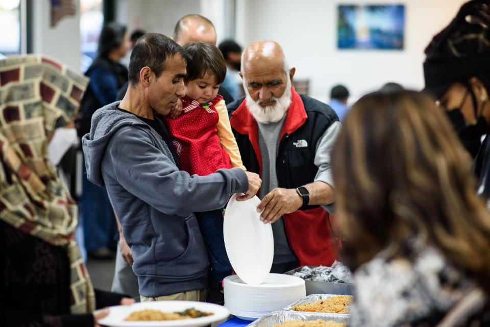 Zikrullah Habibi holds his daughter, Asra, while getting food during a meet up of recent Afghan refugees, veterans and others at Afghan Kabob on Sunday, Nov. 14, 2021.