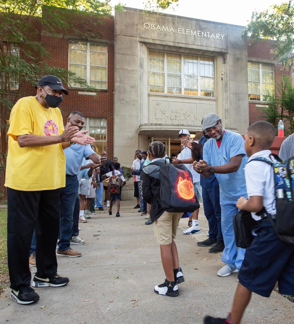 The Watch D.O.G.S. (Dads With Great Students), fathers and grandfathers of Barack H. Obama Magnet School students, cheer on each child as they head into the Jackson, Miss., elementary school on the first day of school Monday, Aug. 7, 2023.
