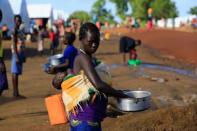 FILE PHOTO: A South Sudanese refugee woman cleans a pot, while carrying a child, at the Palabek Refugee Settlement Camp in Lamwo district, Uganda June 16, 2017. REUTERS/James Akena