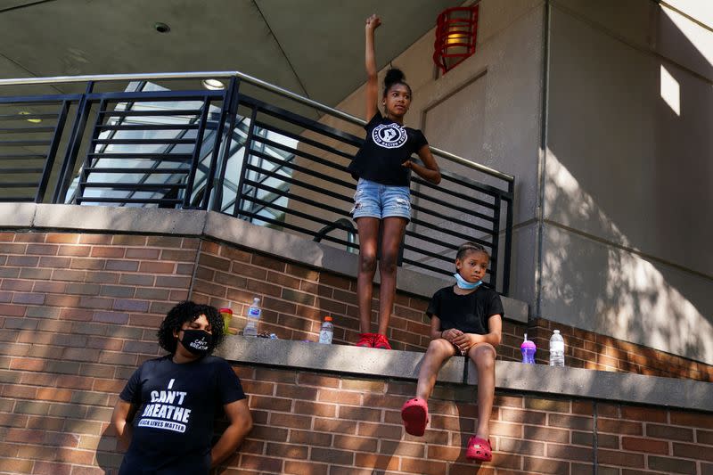 Three sisters participate in a rally against racial inequality and the police shooting death of Rayshard Brooks, in Atlanta