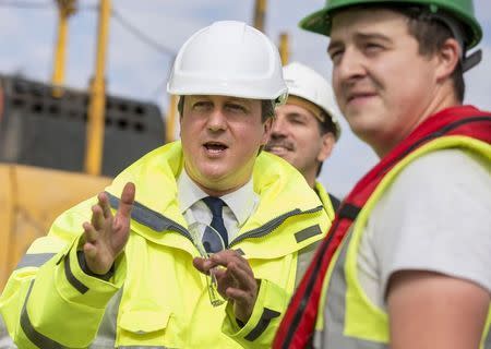 British Prime Minister David Cameron speaks with sea defence workers on a beach at Clacton-on-Sea, Essex, October 2., 2014. REUTERS/Peter Nicholls