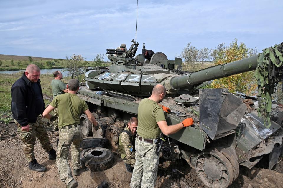 Ukrainian servicemen work on a tank on September 20, 2022, abandoned by Russian troops during their retreat in the north of the Kharkiv region. (Photo by SERGEY BOBOK / AFP) (Photo by SERGEY BOBOK/AFP via Getty Images)