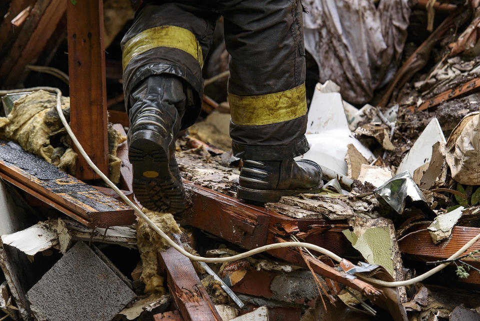 Southern Marin Fire Department members search a crushed house in the aftermath of a mudslide that destroyed three homes on a hillside in Sausalito, Calif., Thursday, Feb. 14, 2019. Waves of heavy rain pounded California on Thursday, filling normally dry creeks and rivers with muddy torrents, flooding roadways and forcing residents to flee their homes in communities scorched by wildfires. (AP Photo/Michael Short)