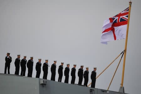 Sailors stand to attention on board HMS Queen Elizabeth, as they wait for the MV Boudicca to leave the harbour in Portsmouth