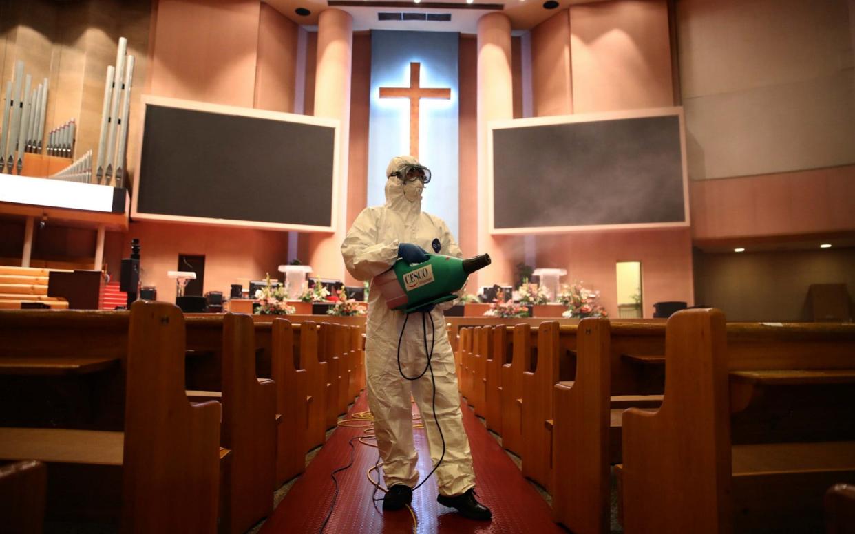 A disinfection worker wearing protective clothing sprays anti-septic solution in an Yoido Full Gospel Church in Seoul  - Getty