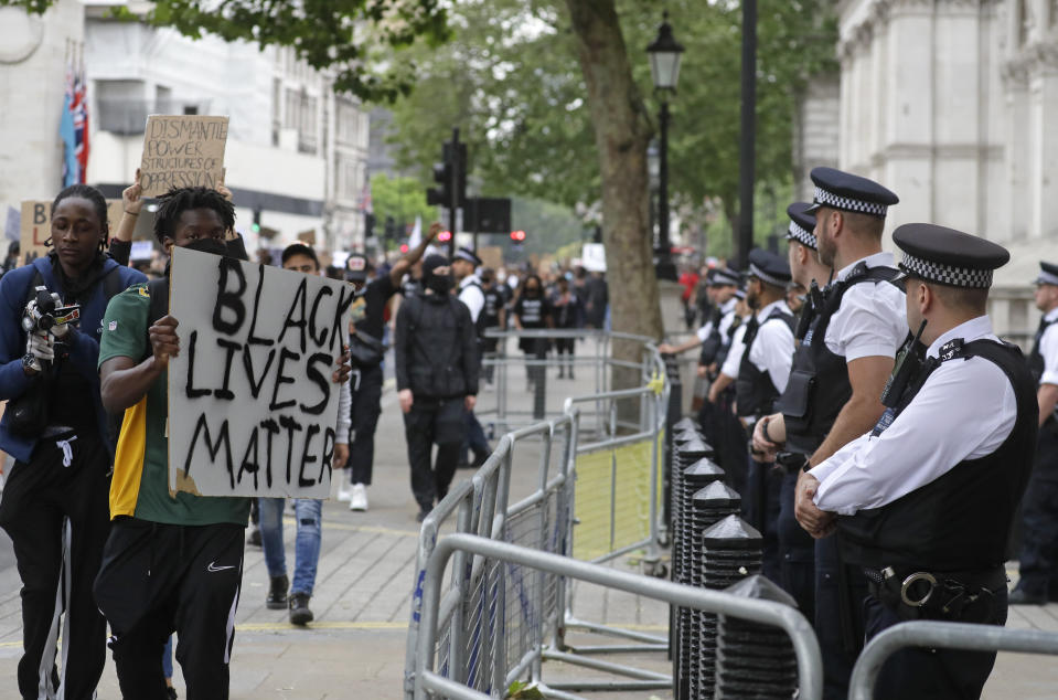 Protesters show a banner to police officers as they march past Downing street in London, Wednesday, June 3, 2020, over the death of George Floyd, a black man who died after being restrained by Minneapolis police officers on May 25. Protests have taken place across America and internationally, after a white Minneapolis police officer pressed his knee against Floyd's neck while the handcuffed black man called out that he couldn't breathe. The officer, Derek Chauvin, has been fired and charged with murder. (AP Photo/Kirsty Wigglesworth)