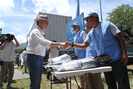 Colombia's President Juan Manuel Santos greets an observer of the UN as the last container with weapons delivered by the rebels of the FARC is turned in, in La Guajira, Colombia August 15, 2017. Colombian Presidency/Handout via REUTERS