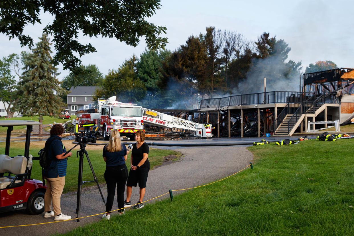 Juday Creek Golf Course clubhouse owner Linda Rogers speaks with a news crew as firefighters work to put out the fire at the clubhouse on Monday, Aug. 26, 2024, in Granger.