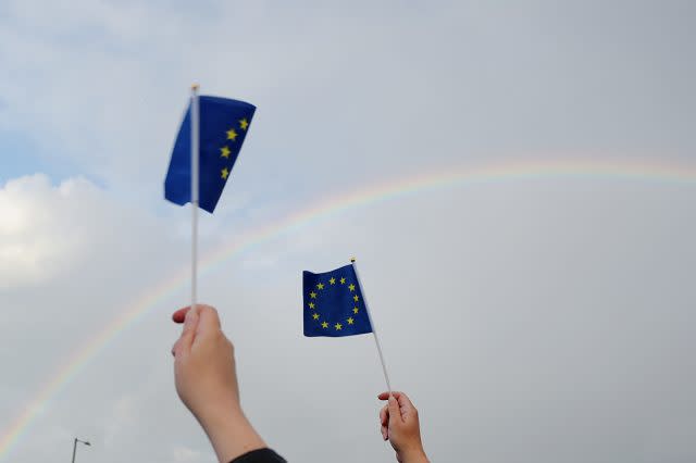 Supporters hold up European Union flags as a rainbow forms in the sky