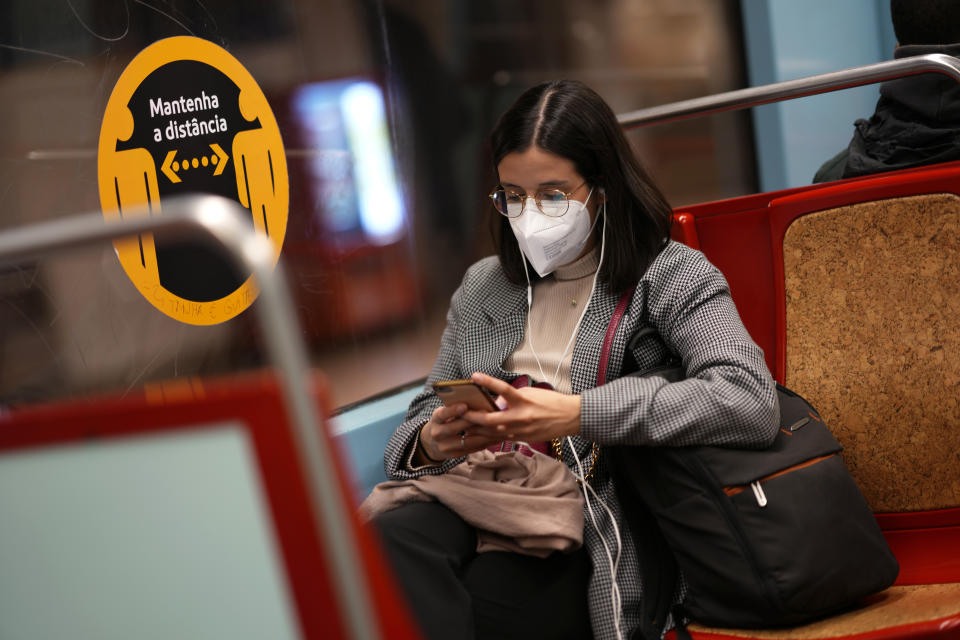 FILE - A woman wearing an FFP2 face mask looks at her phone on a subway train in Lisbon, Thursday, Jan. 6, 2022. Italy, Spain and other European countries are re-instating or stiffening mask mandates as their hospitals struggle with mounting numbers of COVID-19 patients. (AP Photo/Armando Franca, File)