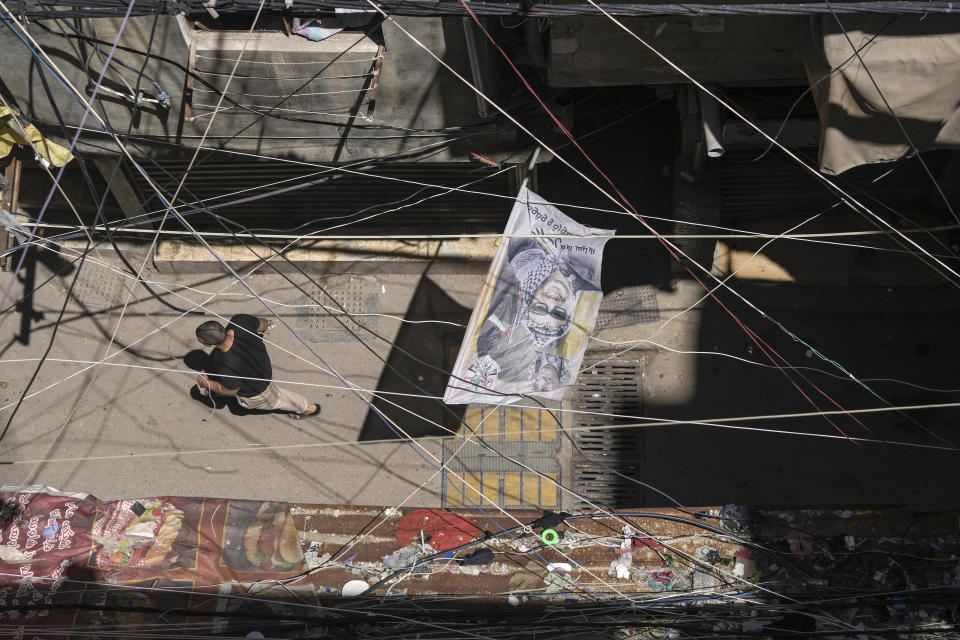 A Palestinian man walks over a flag with the picture of late Palestinian leader Yasser Arafat at the Palestinian refugee camp of Shatila in Beirut, Lebanon, Wednesday, May 15, 2024. The Nakba, Arabic for "catastrophe," refers to the 700,000 Palestinians who fled or were driven out of what today is Israel before and during the war surrounding its creation in 1948. (AP Photo/Hassan Ammar)
