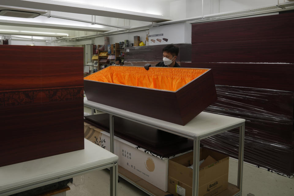 A worker moves a paper coffin at the factory of LifeArt in Hong Kong, Friday, March 18, 2022. Hong Kong is running short of coffins during its deadliest outbreak of the coronavirus pandemic. LifeArt, a company in Hong Kong is trying to make an alternative, cardboard coffin, which it says is environmentally-friendly. (AP Photo/Kin Cheung)