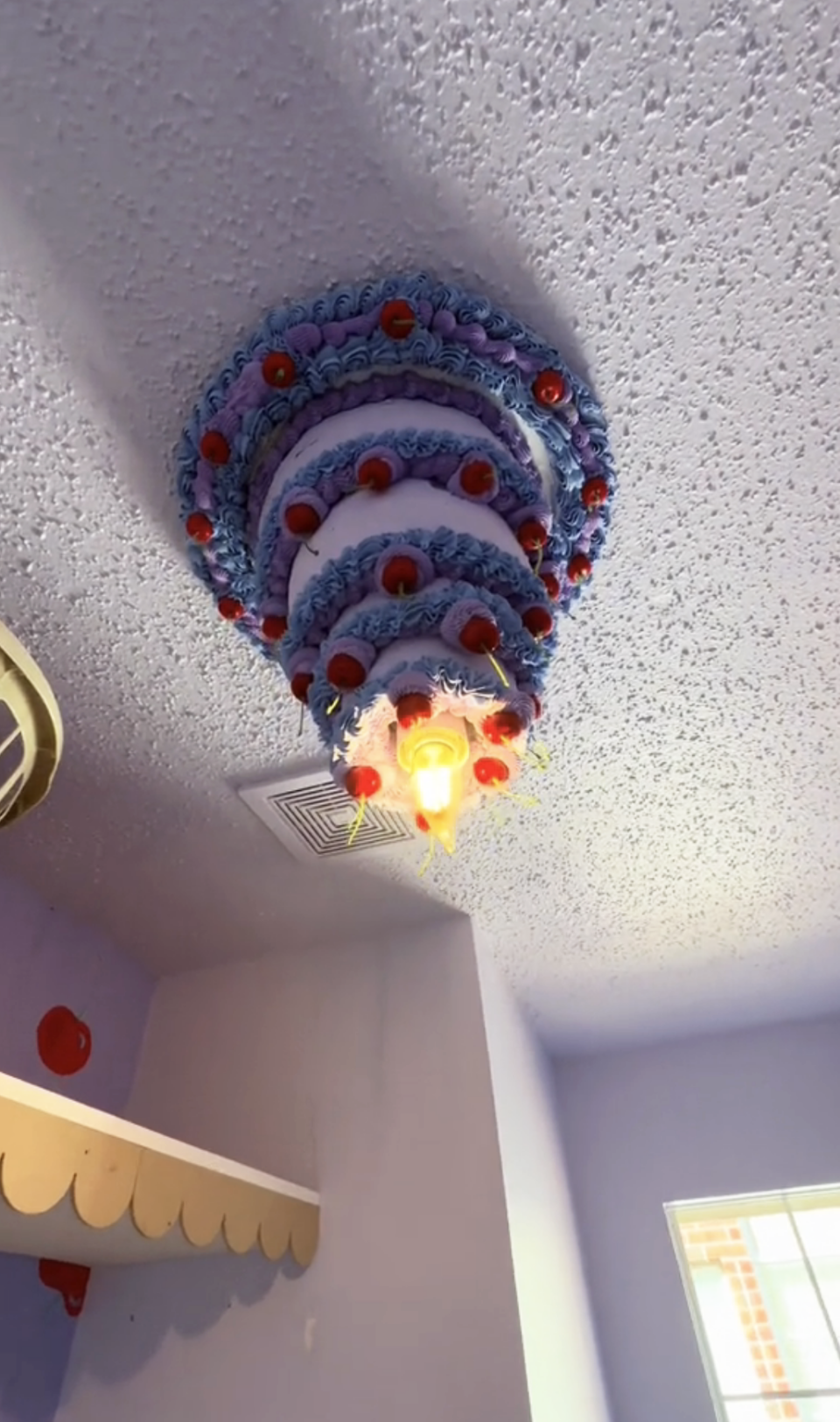 An up-close shot of the cake chandelier, which has multiple layers decorated with icing and cherries