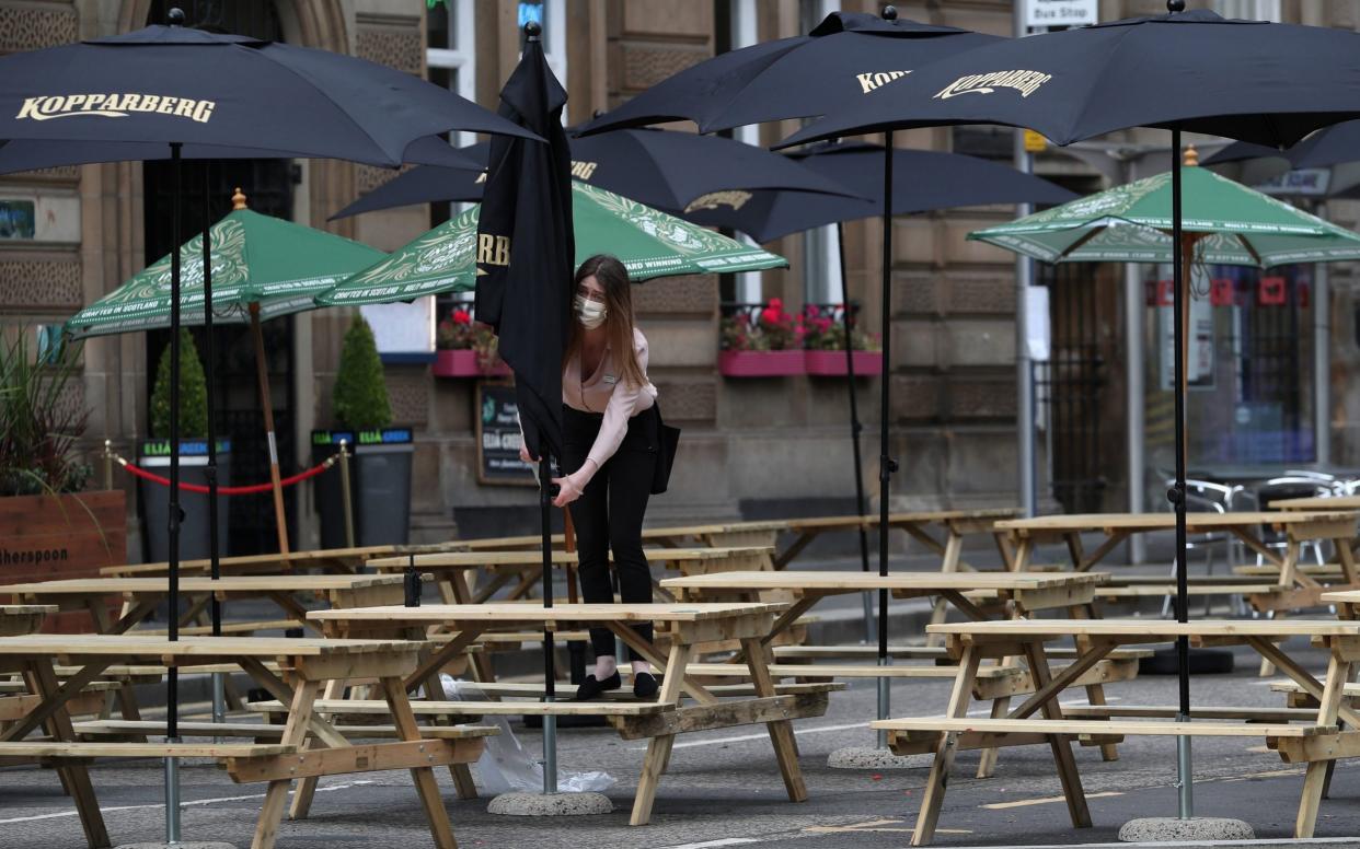 A waitress adjusts a canopy at a restaurant seating area in Glasgow as First Minister Nicola Sturgeon announced the latest coronavirus restrictions - PA