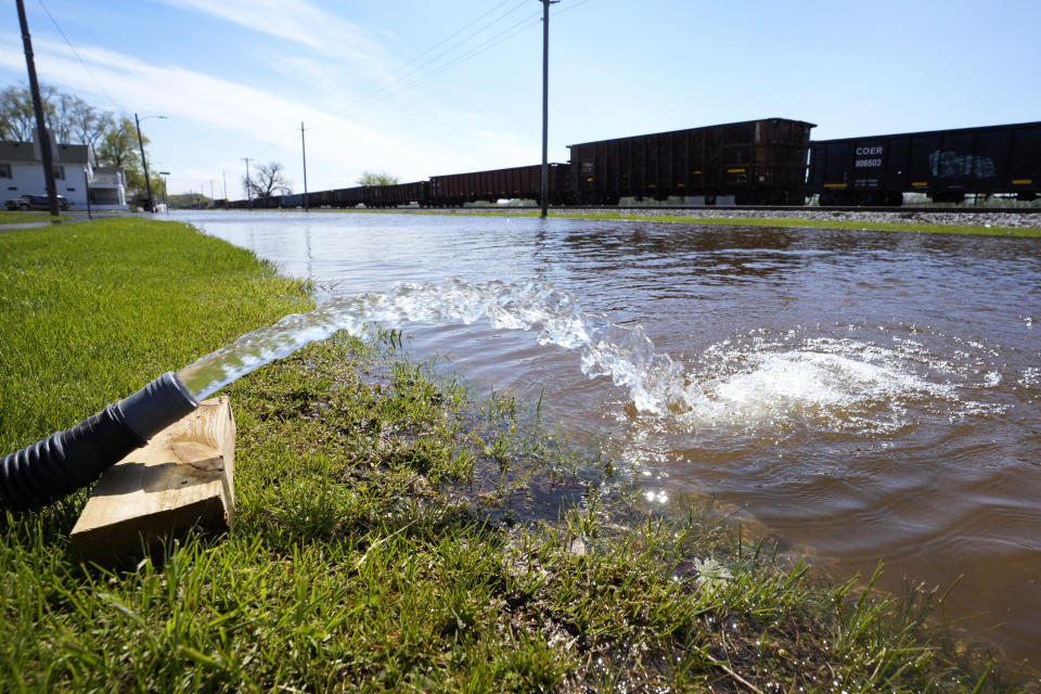 A sump hose hose empties water from a flooded basement, Monday, May 1, 2023, in Buffalo, Iowa. (AP Photo/Charlie Neibergall)