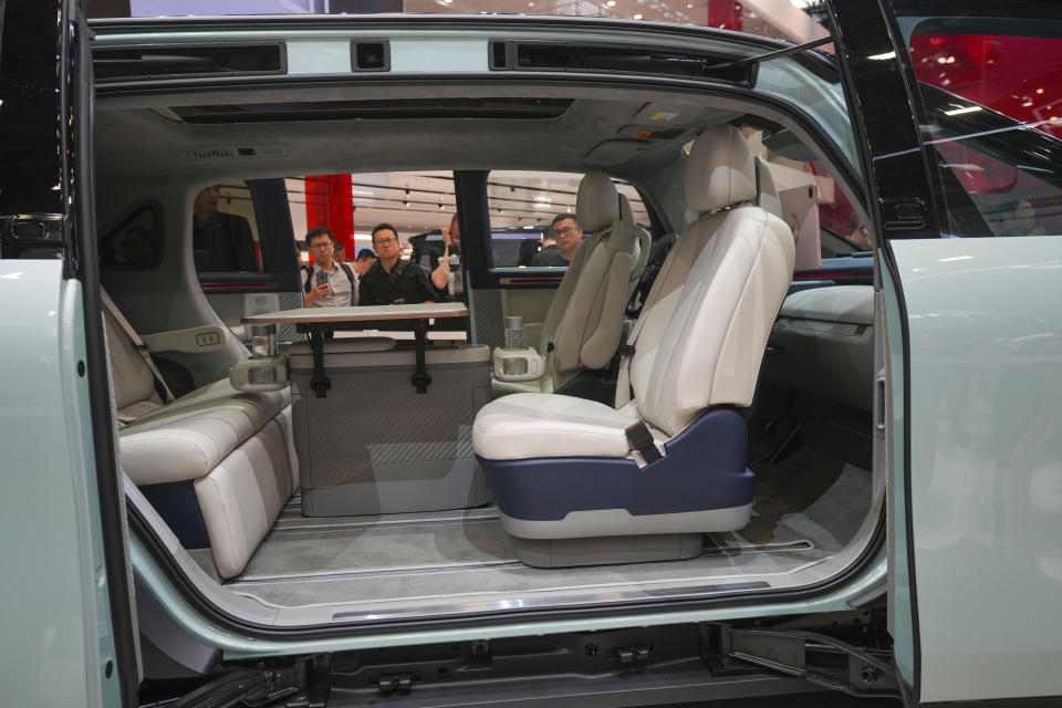 Visitors look at an Exeed C-DM car during the China Auto Show in Beijing, China, Friday, April 26, 2024. China's vision of the future of the automobile electrified and digitally connected is on display at the ongoing Beijing auto show. (AP Photo/Tatan Syuflana)