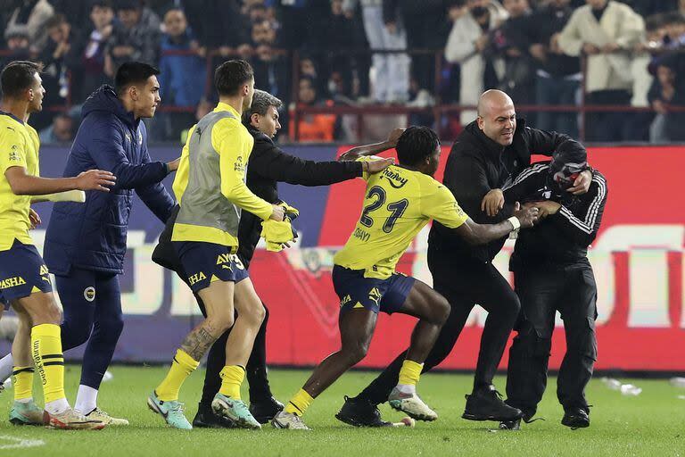 Jugadores de Fenerbahce se defienden de los ataques de los hinchas de Trabzonspor que invadieron el campo tras un partido de la Superliga de Turquía