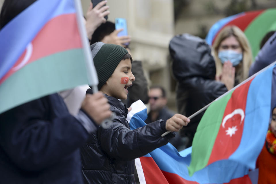 Azerbaijanis with the national flags celebrate after the country's President claimed Azerbaijani forces have taken Shushi, a key city in the Nagorno-Karabakh region that has been under the control of ethnic Armenians for decades in Baku, Azerbaijan, Sunday, Nov. 8, 2020. (AP Photo)