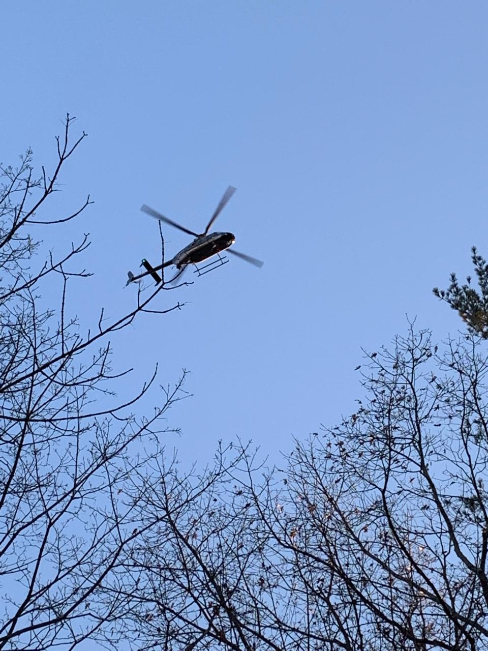 A helicopter flies low Saturday, Dec. 4, 2021. over a back yard in the Bayview Drive neighborhood of Durham searching for a missing University of New Hampshire student.