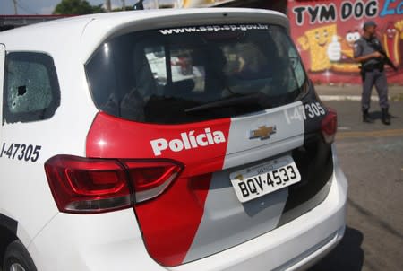 A police vehicle with a window damaged by bullets is seen near a site where an armed gang holds people hostage after they robbed a securities company at the Viracopos airpoart freight terminal, in Campinas