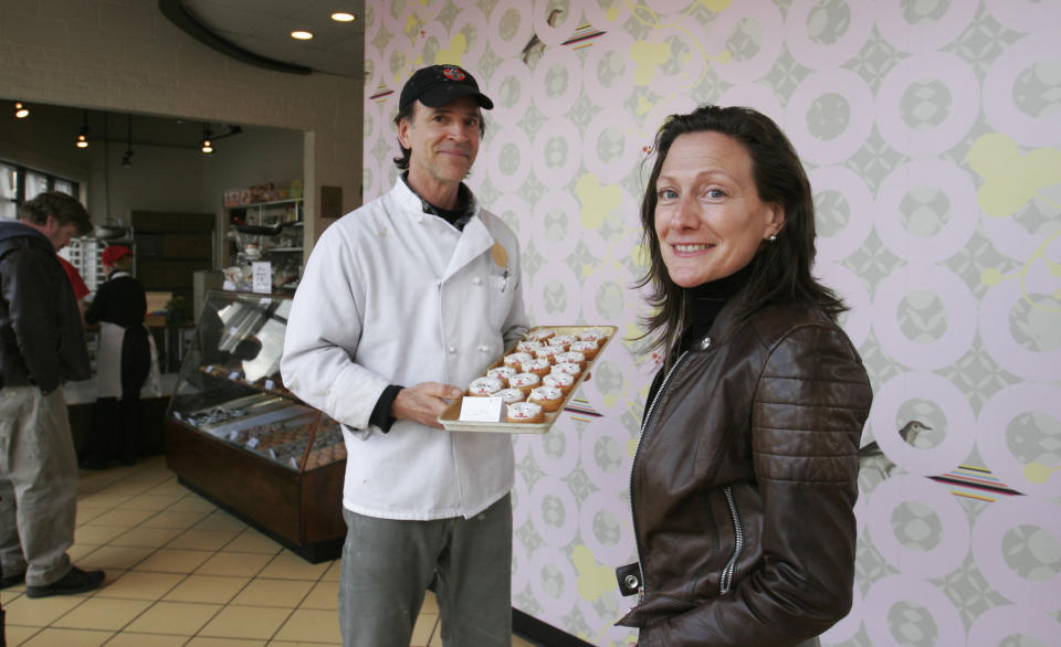 This photo taken Sunday, March 3, 2013, provided by Sarah Rowland shows shop owner J Frank, left, and Sarah Rowland with the wallpaper she designed for Dixie Donuts in Richmond, Va. Owners Betsy Thomas and J Frank asked Rowland to design a custom wallpaper for an accent wall at the shop located in the trendy Carytown section of Richmond. (AP Photo/Sarah Rowland, Jay Paul)