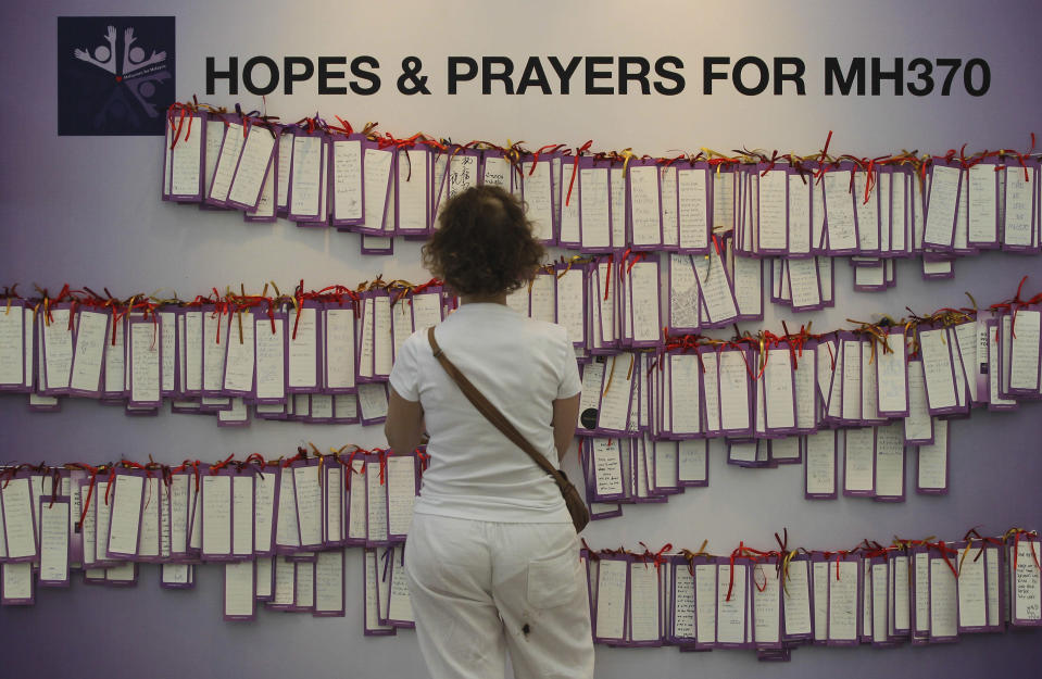 A woman read message cards tied up for passengers aboard a missing Malaysia Airlines plane, at a shopping mall in Kuala Lumpur, Malaysia, Monday, March 24, 2014. A Chinese plane on Monday spotted two white, square-shaped objects in an area identified by satellite imagery as containing possible debris from the missing Malaysian airliner, while the United States separately prepared to send a specialized device that can locate black boxes. (AP Photo)