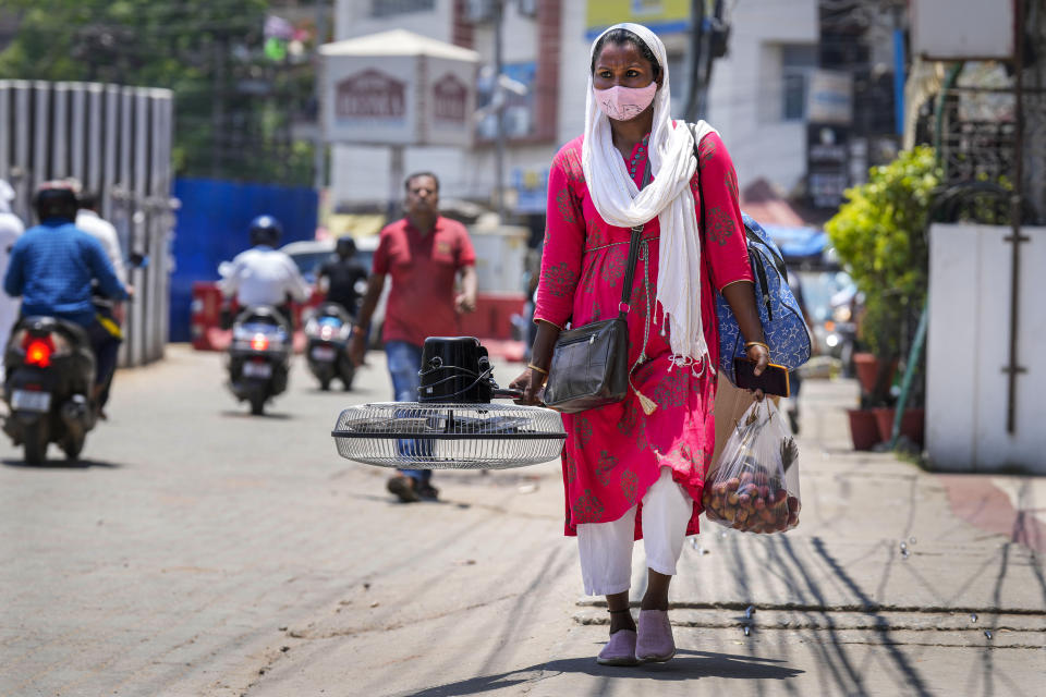 Una mujer carga con un ventilador comprado en un mercado en un día de altas temperaturas en Guwahati, India, el 25 de mayo de 2024. (AP Foto/Anupam Nath)