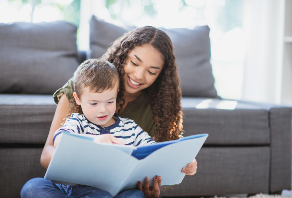 Teenage babysitter reading to a younger child