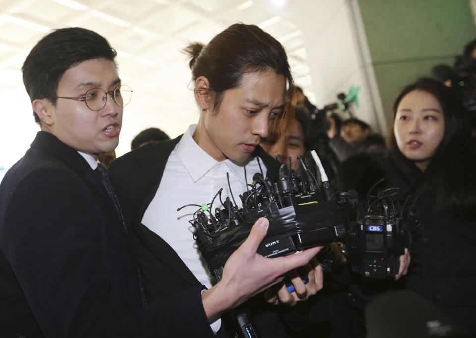 In this March 14, 2019, photo, K-pop singer Jung Joon-young, center, arrives at the Seoul Metropolitan Police Agency in Seoul, South Korea. Police have alleged Jung secretly filmed himself having sex with about 10 women and shared the footage with friends by a mobile messenger app. (AP Photo/Ahn Young-joon)