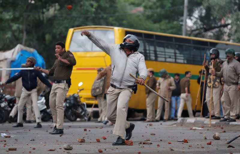 A police officer throws a stone towards protestors during a protest against the Citizenship Amendment Bill in New Delhi