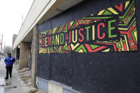 A pedestrian walks past a "DEMAND JUSTICE" sign on a boarded-up storefront on the South Side of Chicago, part of the 6th Police District where officers marked a milestone this fall: They recovered their 1,000th firearm this year. The community is home to neat bungalows, apartment buildings and a modest business strip as well as weed-filled lots, abandoned buildings and other signs of despair. Illegal guns are a major problem in the area; by December police had recovered more than 1,200 firearms. (AP Photo/Nam Y. Huh)