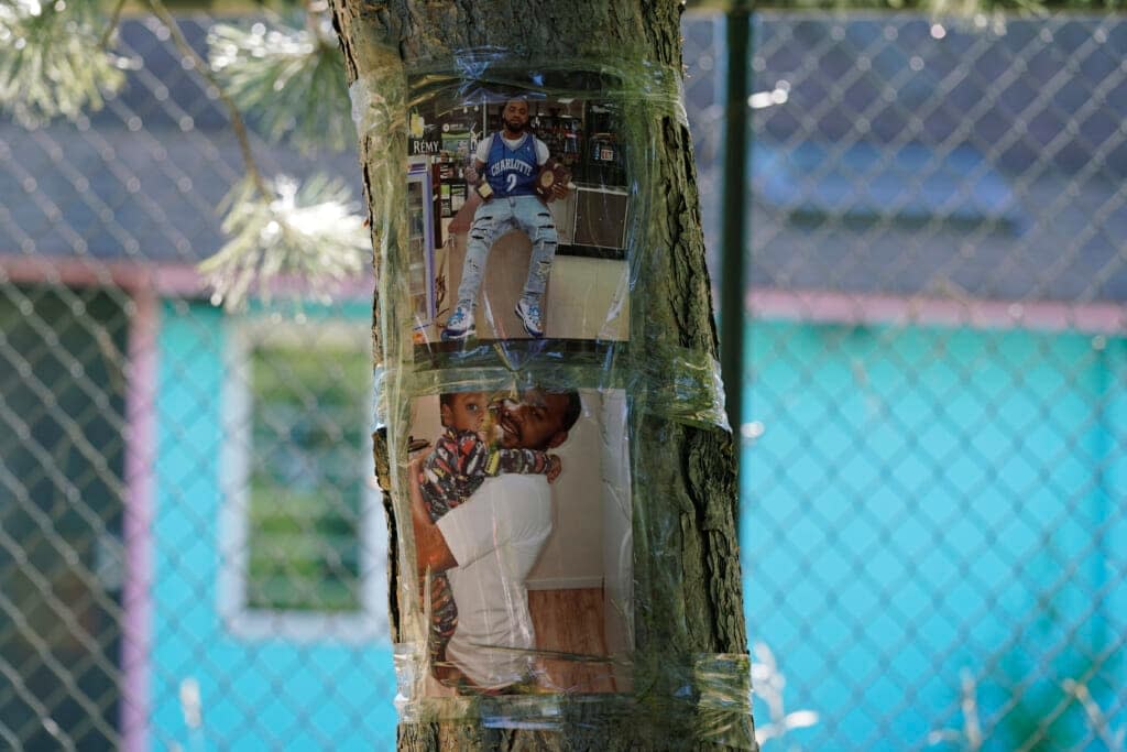 Photos of Christopher Roberts Jr., who was killed in a 2020 shooting in the parking lot of a Safeway store in Seattle’s Rainier Beach neighborhood, are shown taped to a tree at Tuesday, July 12, 2022 near where the shooting too place. (AP Photo/Ted S. Warren)