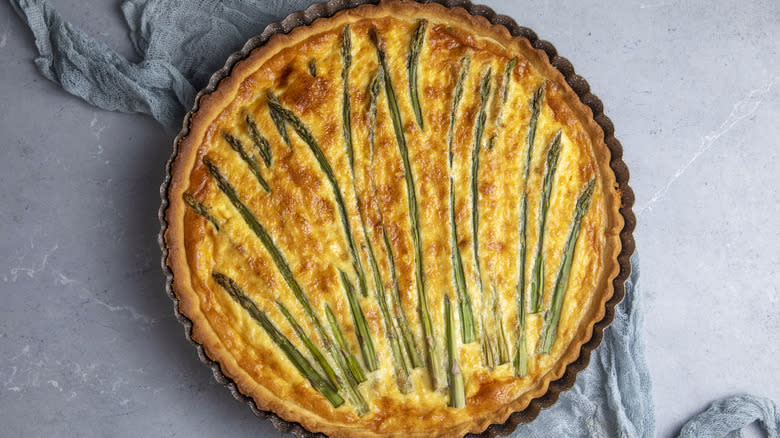 charred asparagus in a baked quiche on a marble surface