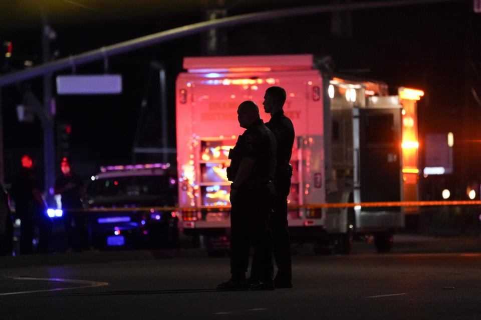 Silhouettes of two police officers near an emergency services vehicle outside the Orange office building.