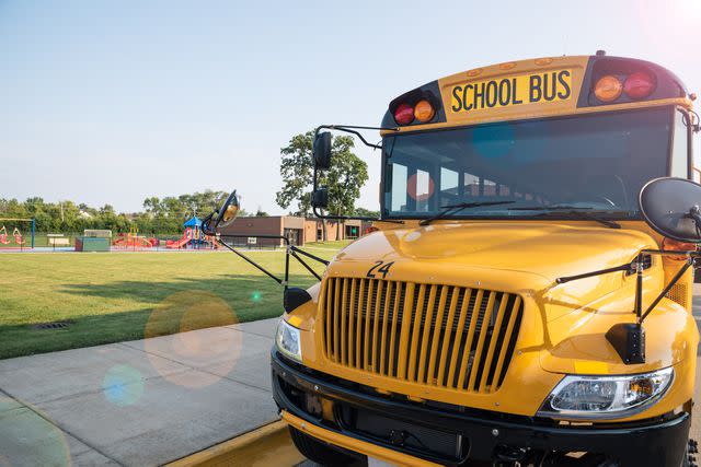 <p>Getty</p> Stock image of school bus in front of school playground.