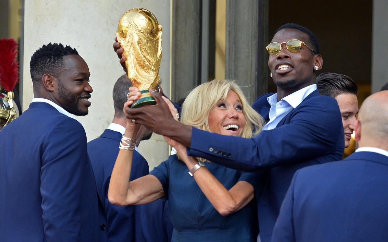 French First Lady Brigitte Macron holds up the World Cup trophy with Paul Pogba as French President Emmanuel Macron receives the France football team during a ceremony at the Elysee Palace on July 16 - Getty Images Europe