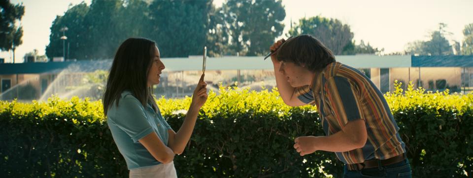 Alana Haim holds a mirror up for Cooper Hoffman while he fixes his hair